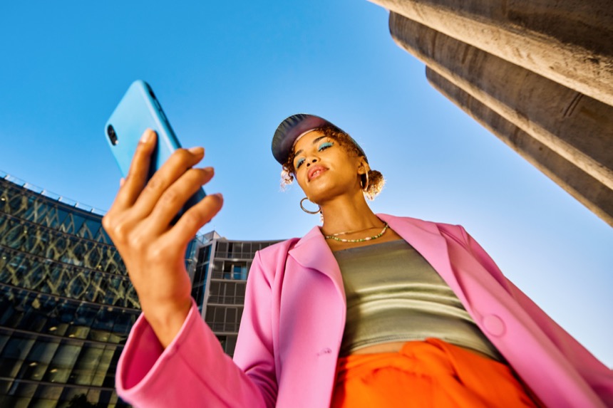 Persoon in roze blazer kijkt naar een telefoon in de lucht.
